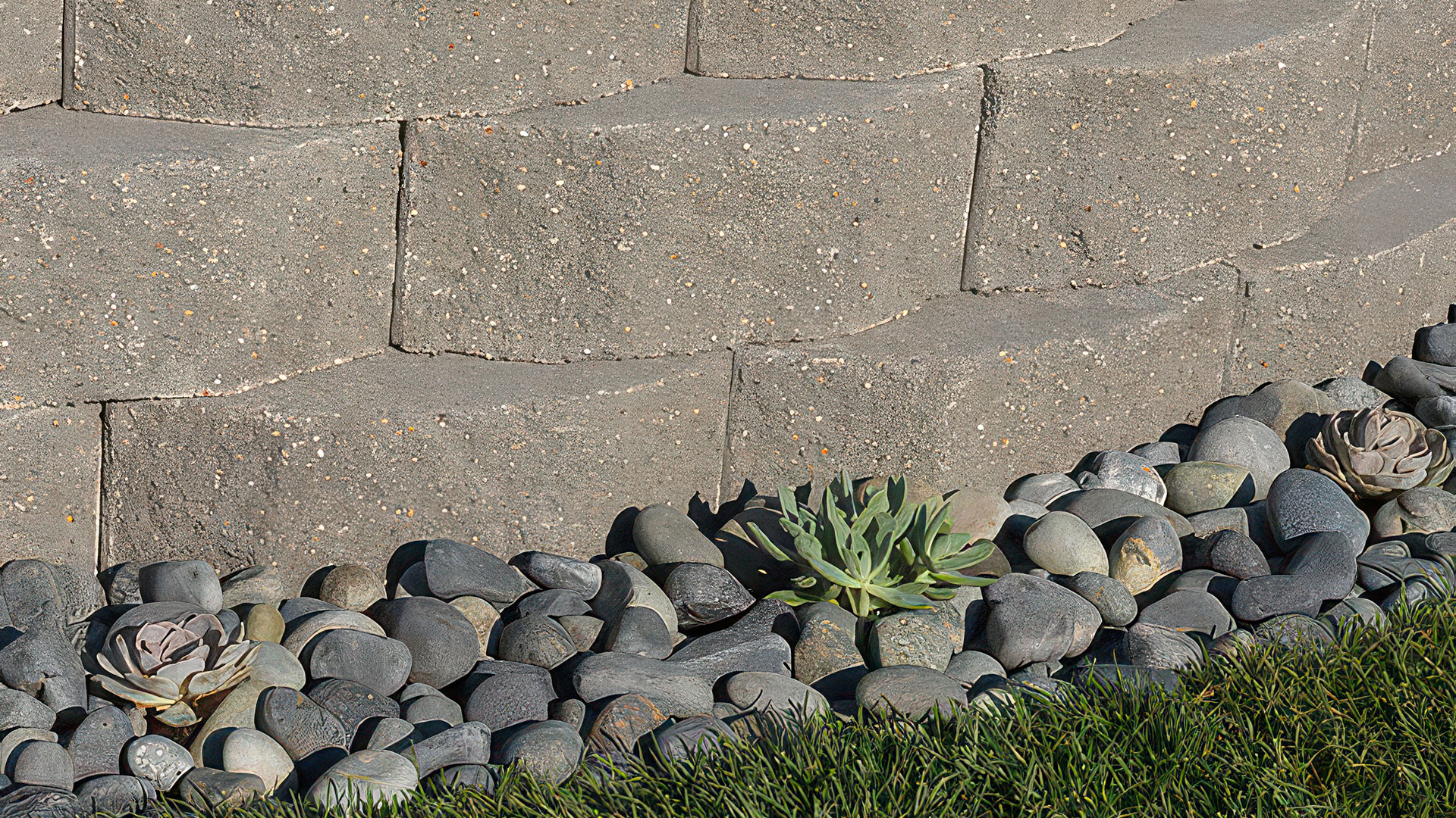 16 inch solid charcoal planter wall with river rocks around the base.