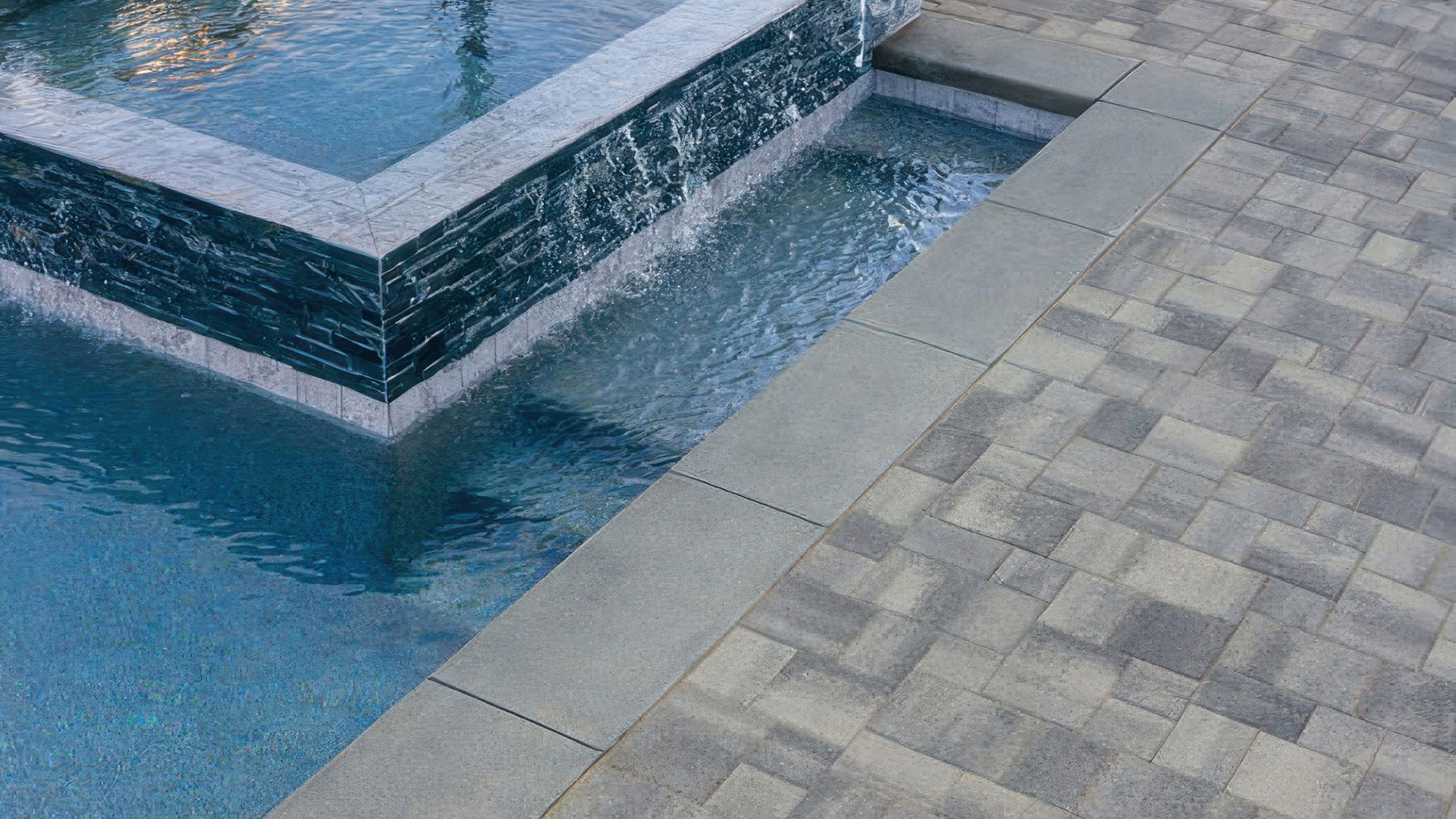 Gray Charcoal Courtyard Stone paving stones installed around outdoor pool deck.