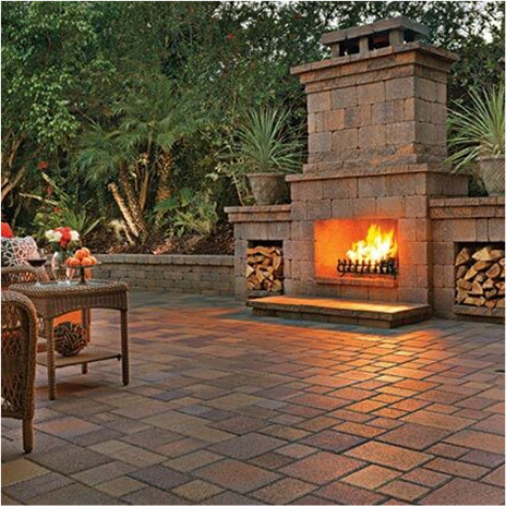 Outdoor fireplace with wood storage on both sides and a seating area in front of it. fireplace is built with blended tuscan rustic wall stone. seating wall is built with 50/50 blend of blended sand stone mocha and tuscan courtyard stone paving stones installed in a ashlar pattern.