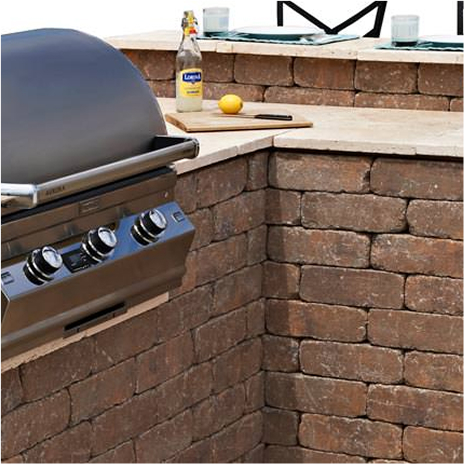 l shaped outdoor kitchen built using rustic wall stone with bbq and optional bar.