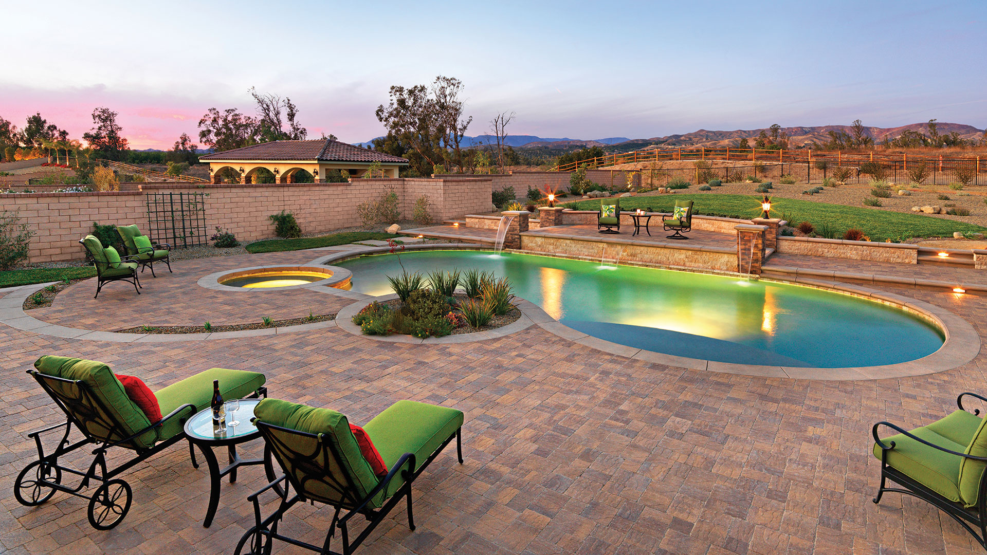 An amazing outdoor pool deck and patio with a sunset. Pool deck and patio are covered with Blended sand stone mocha slate stone paving stones installed in a random ashlar pattern.