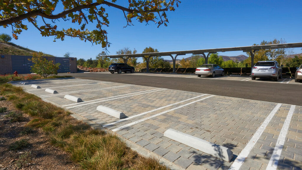 Parking lot paved with 80mm SF Rima in a stack bond pattern using Gray-Moss-Charcoal color. Clearly defined parking stalls feature painted white lines and concrete wheel stops for organization and safety.