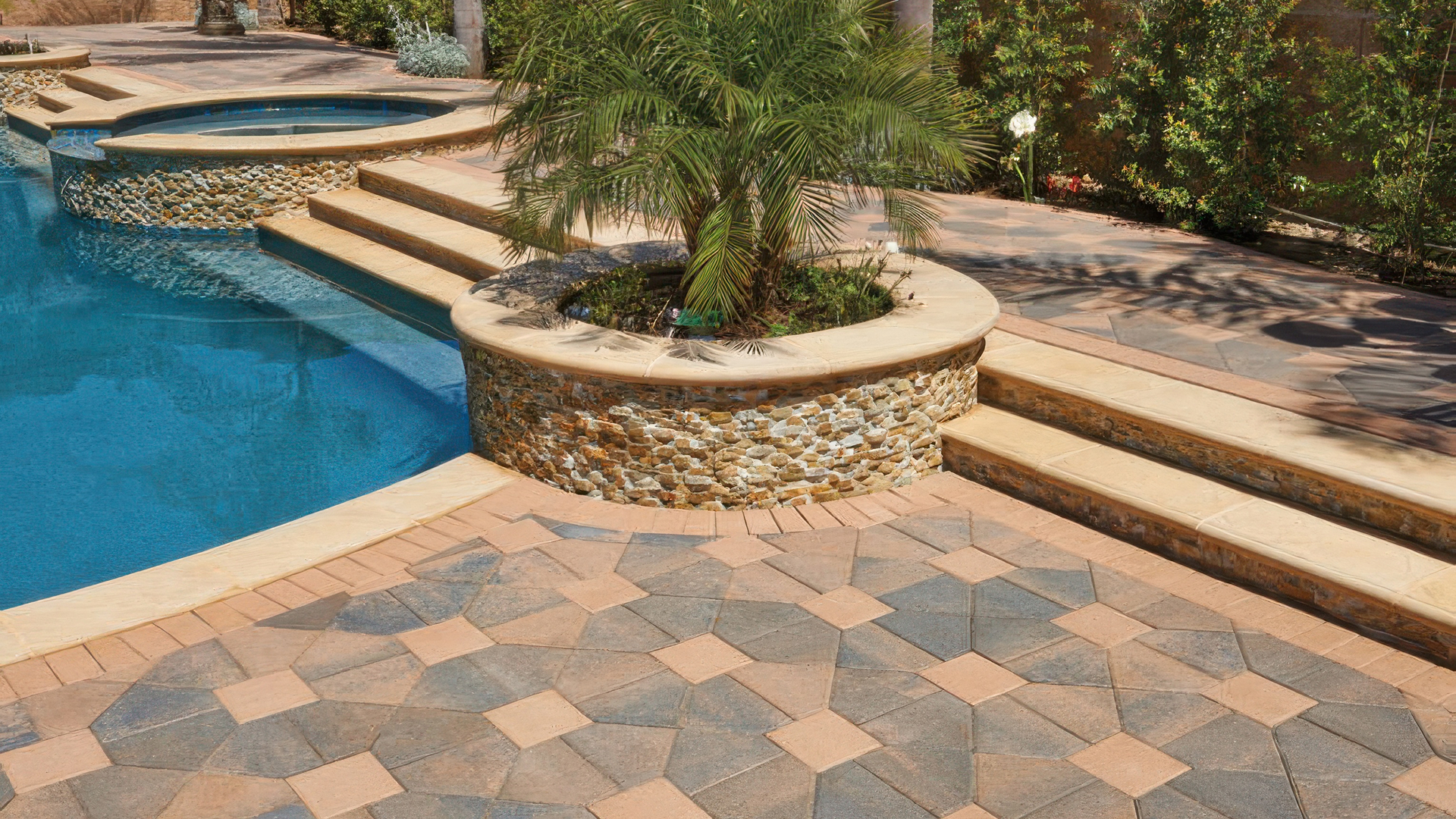 Elegant poolside patio featuring Cream-Brown-Charcoal Bishops Hat pavers paired with Cream 8x8 pavers, arranged in a Venetian parquet pattern. A solid Cream Holland paver border outlines the design. The area includes a raised spa, curved planters with stacked stone veneer, and wide stone steps leading to different levels, surrounded by lush greenery and a palm tree centerpiece.