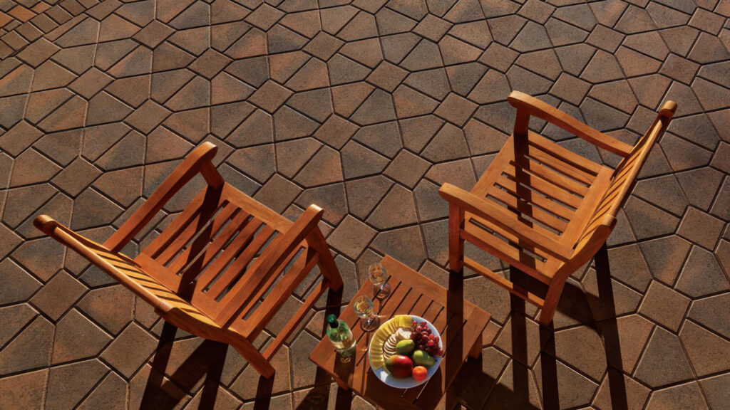 Outdoor patio featuring two wooden chairs and a small table with wine glasses and fruit, set atop Cream-Brown-Charcoal Bishops Hat pavers with solid Brown 8x8 inserts, arranged in a distinctive Venetian parquet pattern.