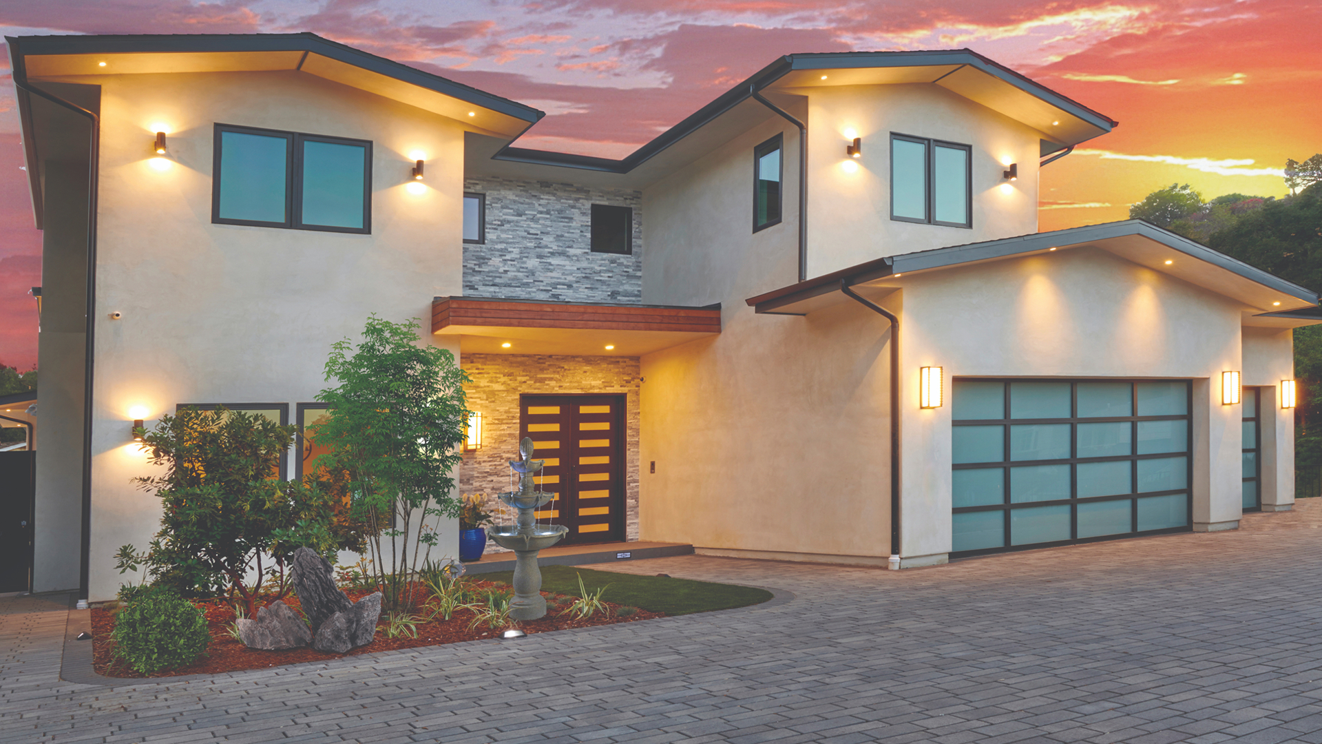 Sleek custom home with driveway in front covered in blended dark gray pewter charcoal permeable aqualina paving stones. installed in a random ashlar pattern.