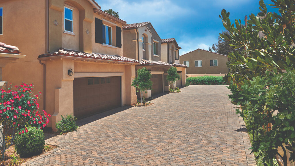 Tuscan color Permeable Holland pavers installed in a running bond pattern form the main surface of this residential driveway. A border of matching Tuscan Permeable Holland pavers is installed in a soldier course, defining the edge along the stucco-finished garages and landscaping.