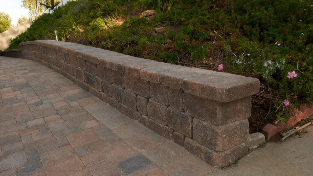 Curb wall made of Stonewall II block and cap in Cream-Brown-Charcoal. Driveway paved with Cream-Brown-Charcoal Castle Cobble I and II (tumbled) in an ashlar pattern.