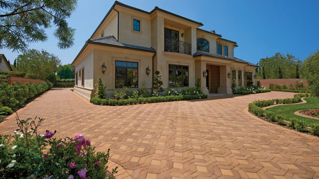 Elegant driveway featuring Cream-Brown Symetry® pavers combined with solid Cream 6x6 stones, installed in a Venetian parquet pattern, complementing the classic architecture and manicured landscaping of the home.