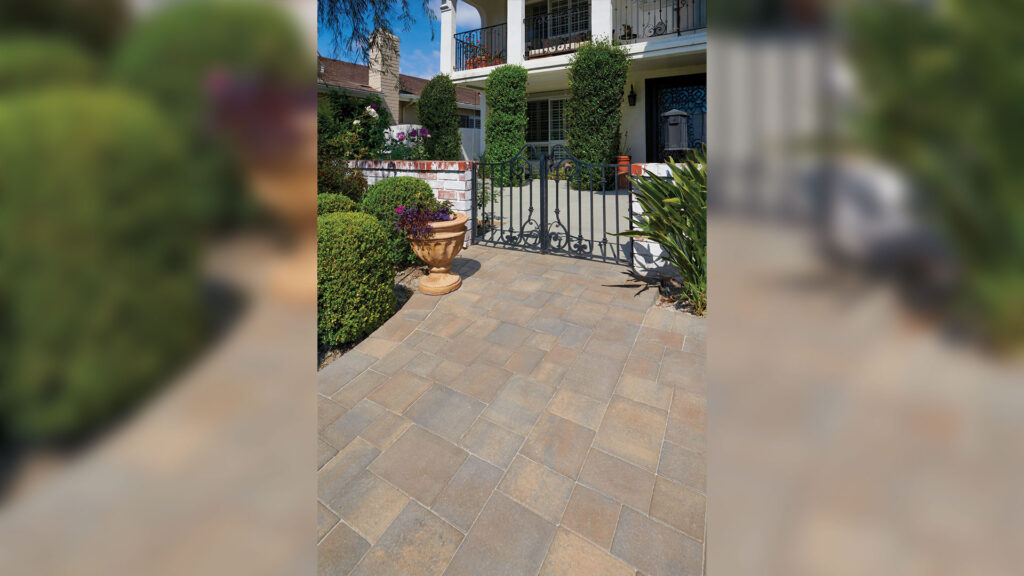 Walkway and entry patio featuring Porcellana 9-inch pavers in Stone-Mocha-Charcoal installed in a random ashlar pattern. The multitone porcelain pavers create a refined approach to a gated courtyard entrance, complemented by manicured hedges, decorative planters, and wrought-iron details that enhance the home's traditional architecture.