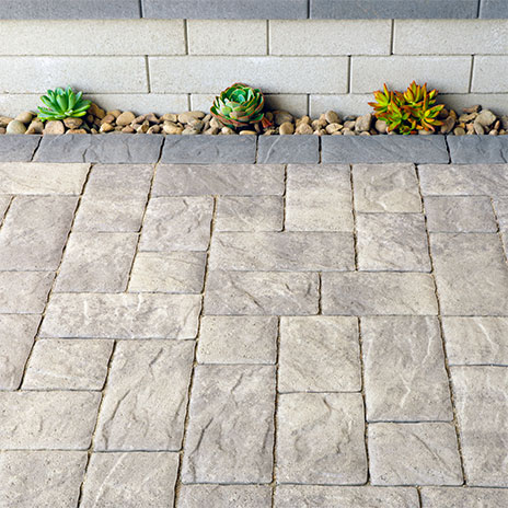Gray-Charcoal Portofino paving stones installed in a random ashlar pattern with a solid Charcoal random runner border along a raised planter wall.